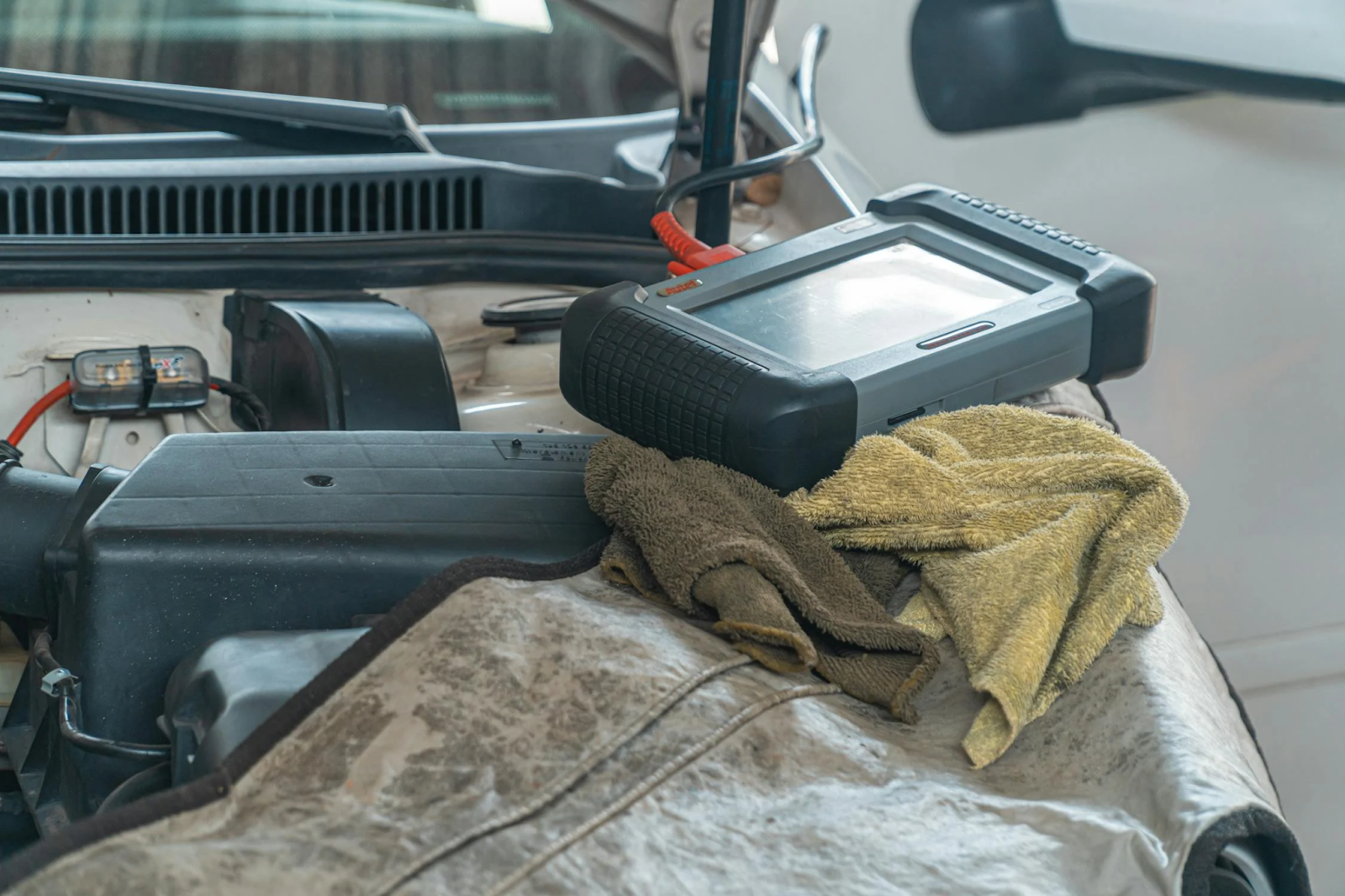 A car with its engine exposed and a battery placed on top, illustrating automotive components for a blog post.